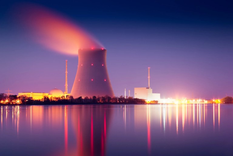 Single nuclear power plant cooling tower glowing red for seismic activity
