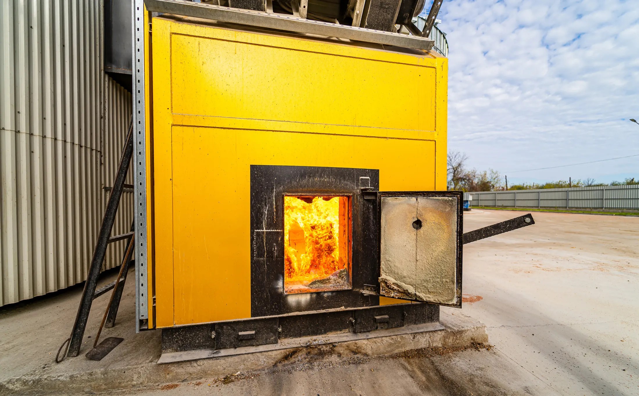 Yellow wood burning stove outside powering biofuel facility in need of pyrometer rating