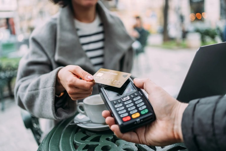 Woman tapping credit card on outside cafe terminal for ANSI X9.119-1 encryption