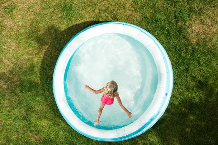 Young girl enjoying summer by leaping into a ASTM F2666-16 aboveground residential pool.