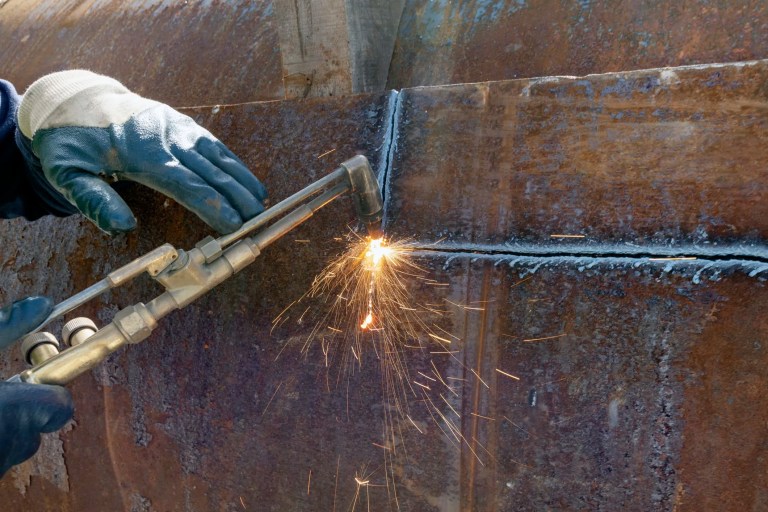 Oxy-Fuel Torch being used for CGA E-5-2017 cutting of rusty steel plate