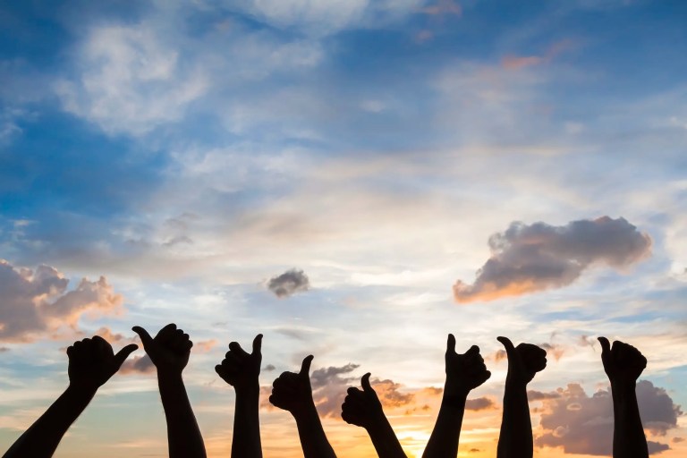 8 thumbs up silhouettes being held up to sunset sky to show ISO 26000 social responsibility