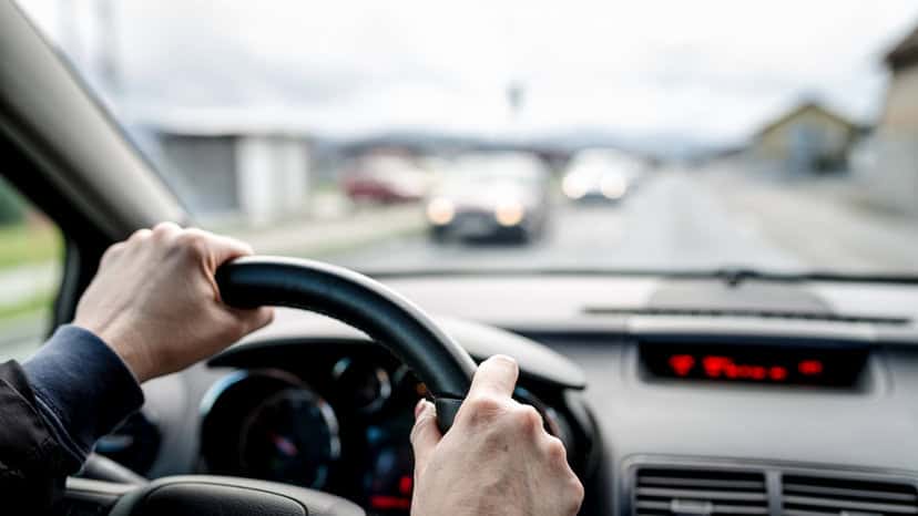 Two hands on wheel driving a car while practicing safe practices in ANSI/ASSP Z15.1-2024: