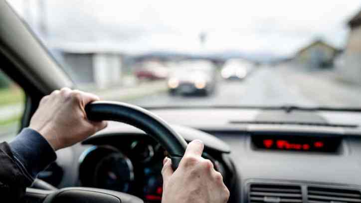 Two hands on wheel driving a car while practicing safe practices in ANSI/ASSP Z15.1-2024: