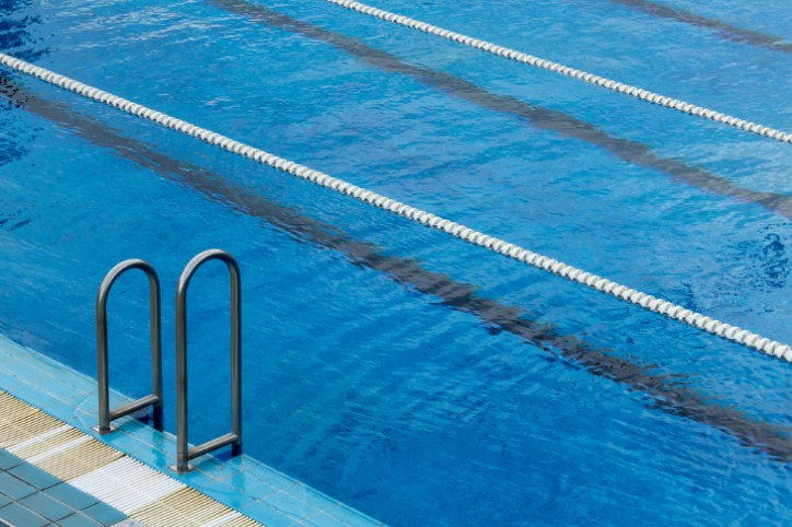 Bright blue swimming pool with chrome ladder and NFPA 70 national electrical code adherence.