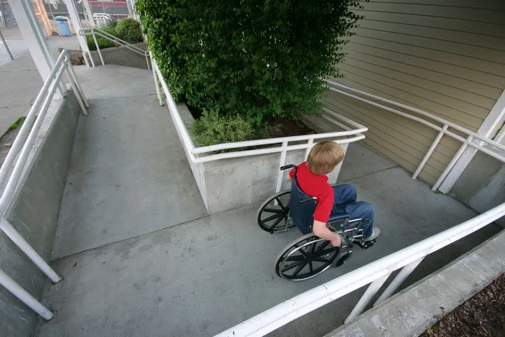 Young boy in wheelchair using ANSI A117.1-2017 ramp