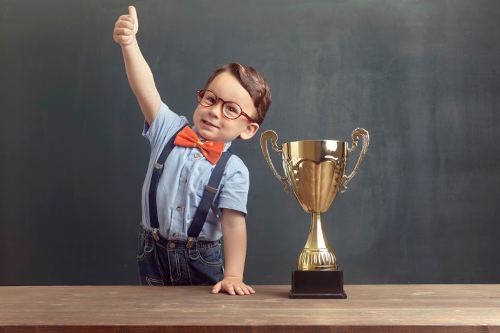 Young champion of the ANSI student paper competition wearing a bowtie and giving thumbs up.
