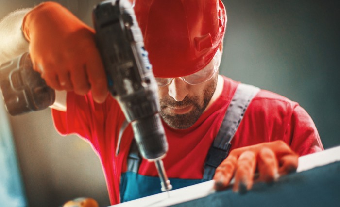 Man drilling screw into wood and might be suffering from hand-arm shocks, in need of ISO 15694.