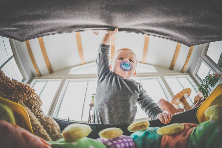 A baby opening a toy box filled with toys that follow ISO 8124 Standards