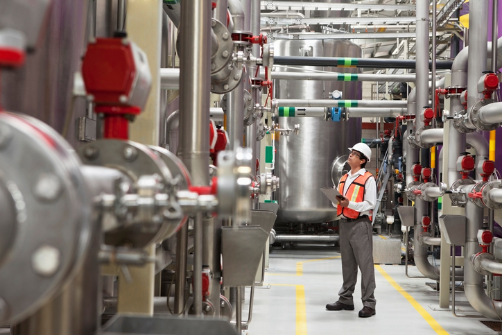 An auditor in a factory trying to plan, do, check, and act, with the PCDA cycle found in ISO 45001