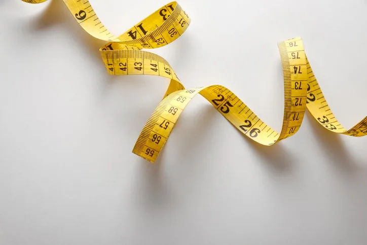 Twisting measuring tape representing the metric system (SI units), which are reflected in standards by an M.