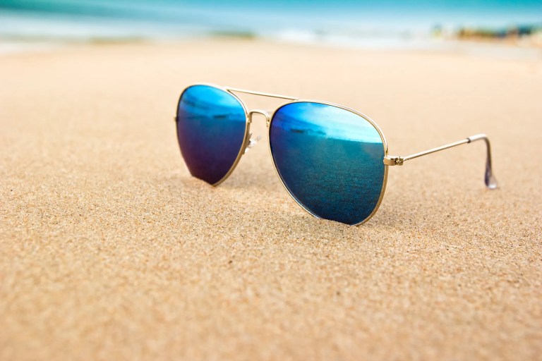 A cool pair of ANSI Z80.3:2025 sunglasses on the beach