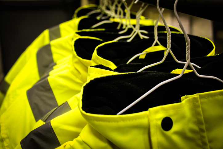Line of yellow HVSA protective suits hung up to show what ISO 45001 does not cover for OH&S management systems.