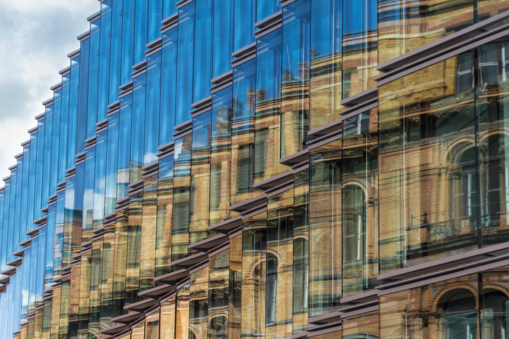 Side of a building with a lot of glass windows that follow the guidelines set in ANSI ASHRAE IES Standard 100