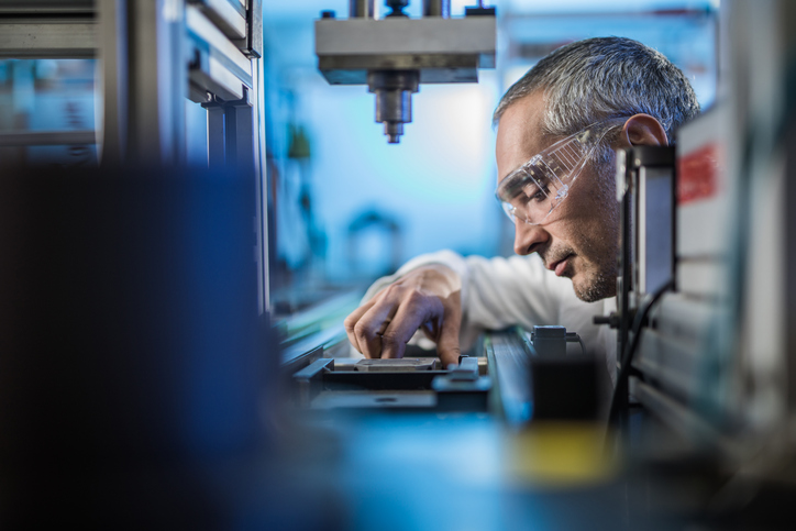 Older scientist analyzing test sample to determine test method precision via ASTM E691.
