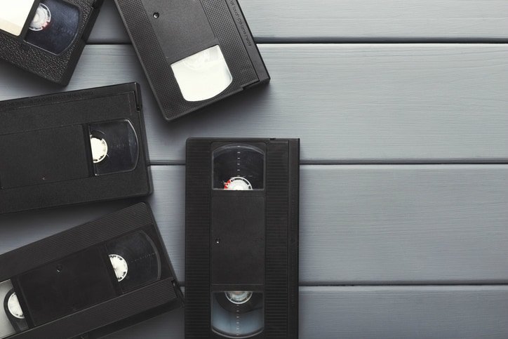 Loose old VHS tapes piled on slatted surface following MPEG-1 suite from ISO IEC 11172.