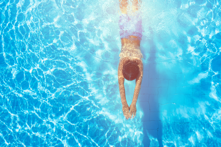 A boy diving into blue water free of Cryptosporidium thanks to APSP professionals.