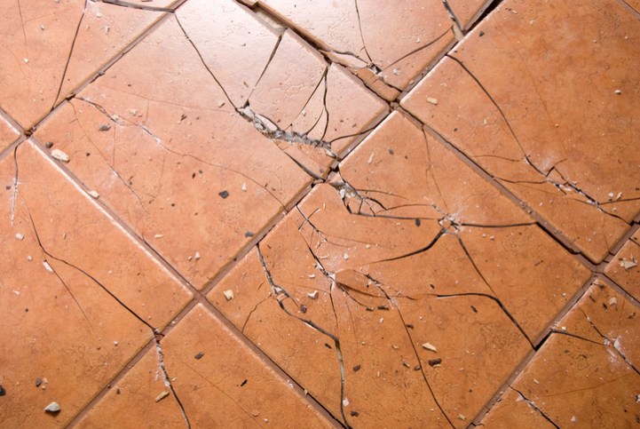 Tan ceramic tiles have been cracked and destroyed after an impact falling steel ball ASTM C1870 test.