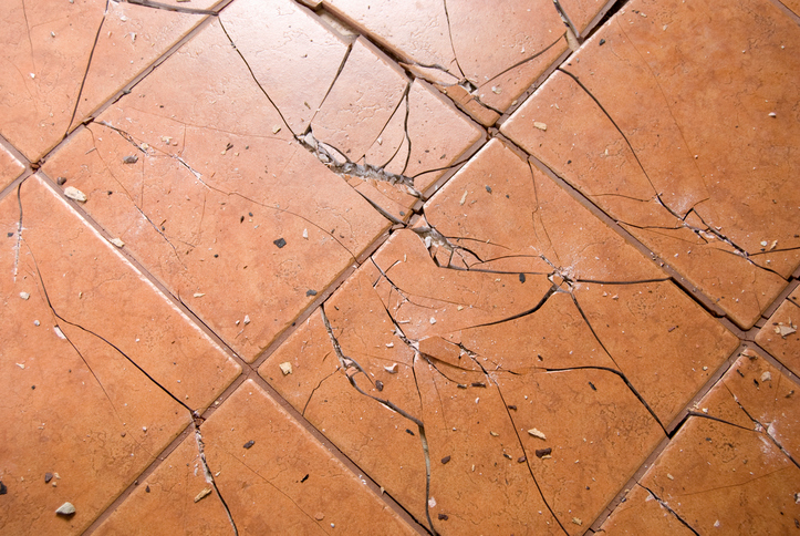 Tan ceramic tiles have been cracked and destroyed after an impact falling steel ball ASTM C1870 test.