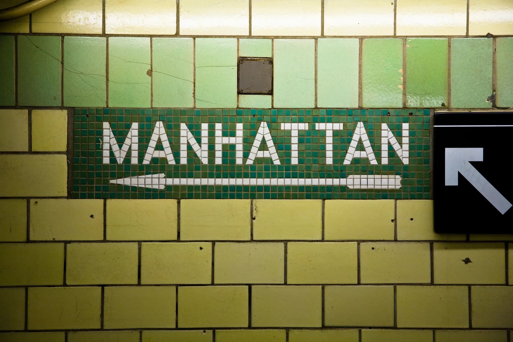 New York City subway station showing which direction is Manhattan, where you can find the rats from commensalism.