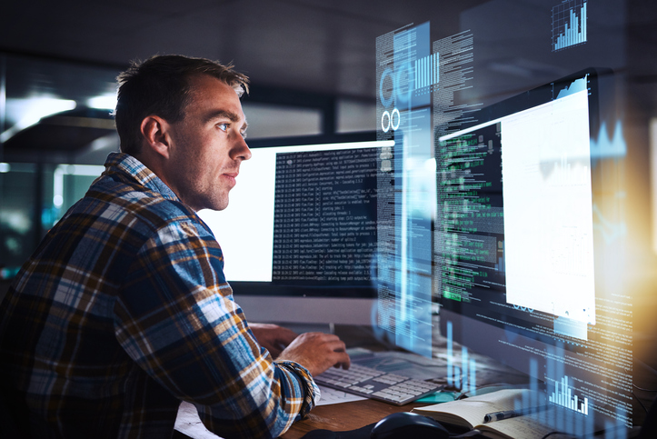 A man coding on a computer that has been assigned to him through Role Based Access Control INCITS 359