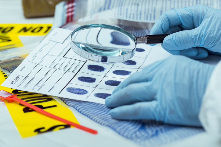 Gloved forensic professional using the ANSI ASB 007 practice to search fingerprints.