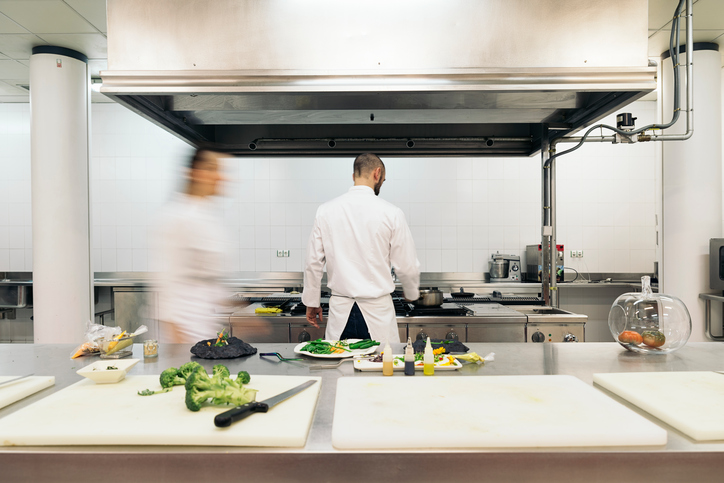 Chef hard at work fighting the dinner crowd under a kitchen exhaust system cleaned with ANSI/IKECA C10-2021.