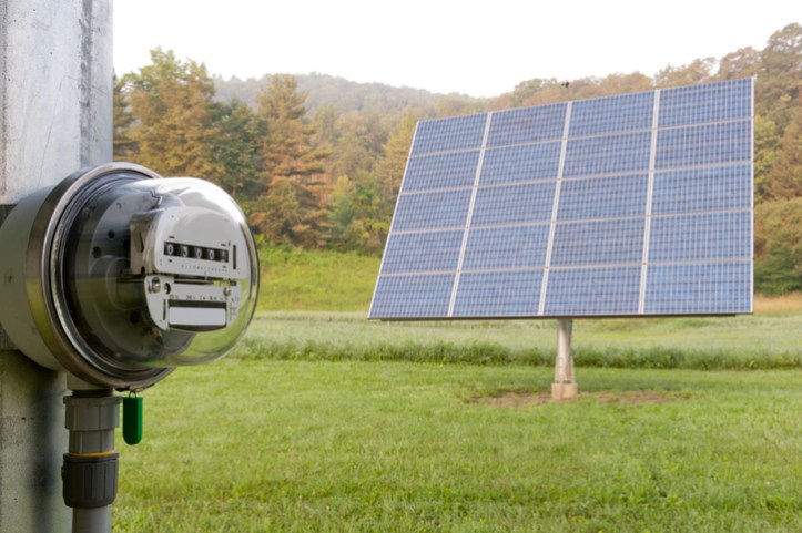 A solar PV panel in the grass connects to an electrical meter to measure energy management with ISO 50001:2018.