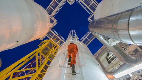 Worker in orange jumpsuit climbing to change power piping to ASME B31.1-2020.