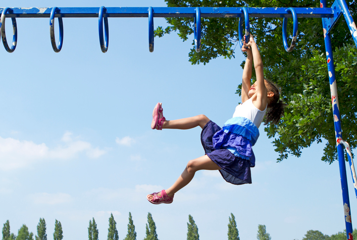 Girl hanging on blue home playground safety designed with ASTM F1148