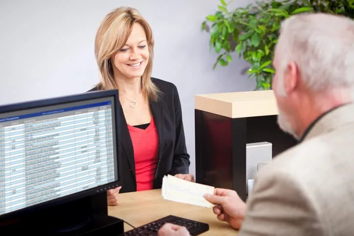 Businesswoman handing in a check to turn into an ANSI X9.100-140-2018 IRD.