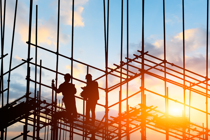 Two workers on a construction site that follows the safety guidelines of NFPA 241-2019