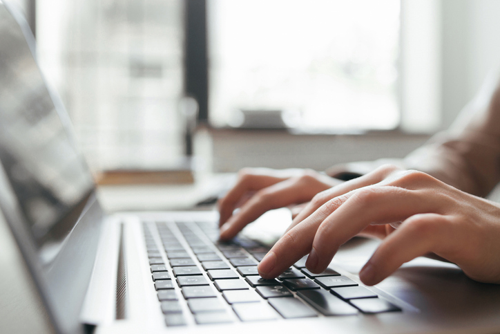 Hands typing on the keyboard of a laptop that follows IEEE 1012 2016