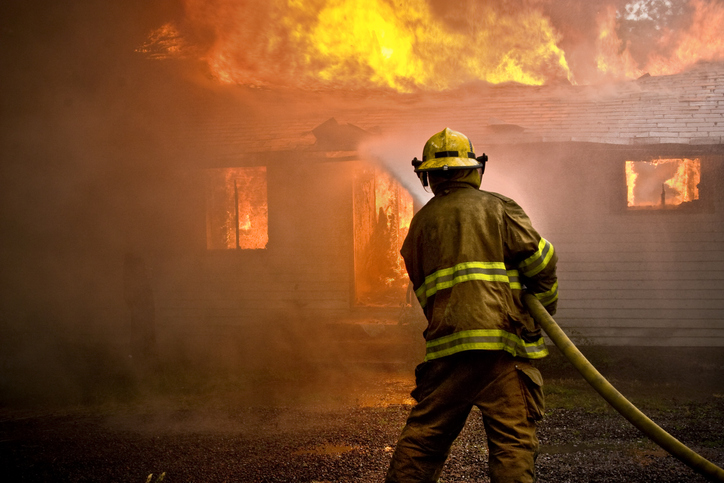 Firefighter utilizing NFPA 1001-2019 professional qualifications to use hose to extinguish ranch home fire