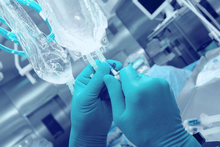 Nurse in blue gloves preparing ISO 15747:2018 plastic containers for intravenous injections.