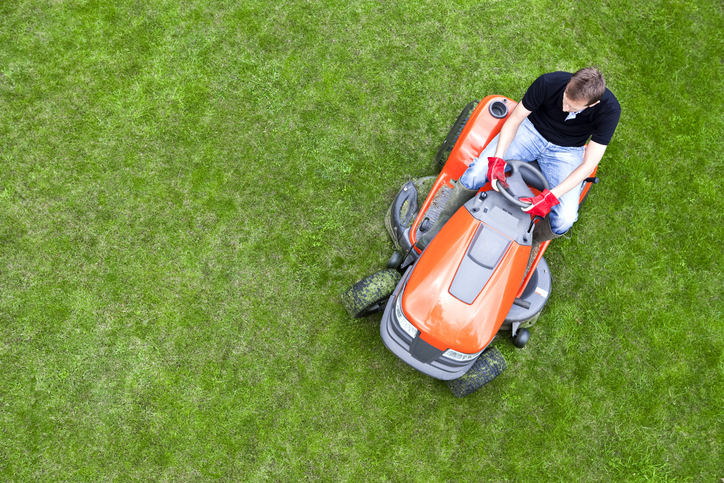 Riding a lawnmower over green grass following ANSI/OPEI B71.10-2018 gasoline fuel systems.