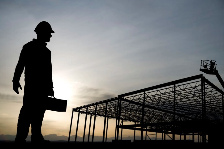 Worker silhouette carrying all ASME B30 safety standards for machine lifting equipment in construction.