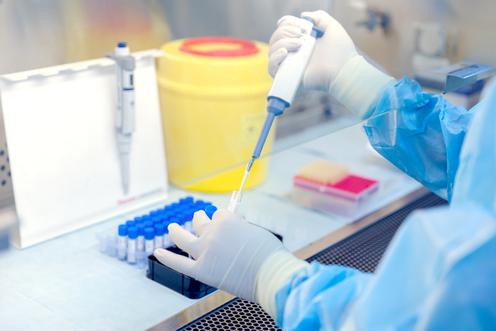 Working in a blue cleanroom and handling a pipette to ANSI and ISO laboratory requirements.
