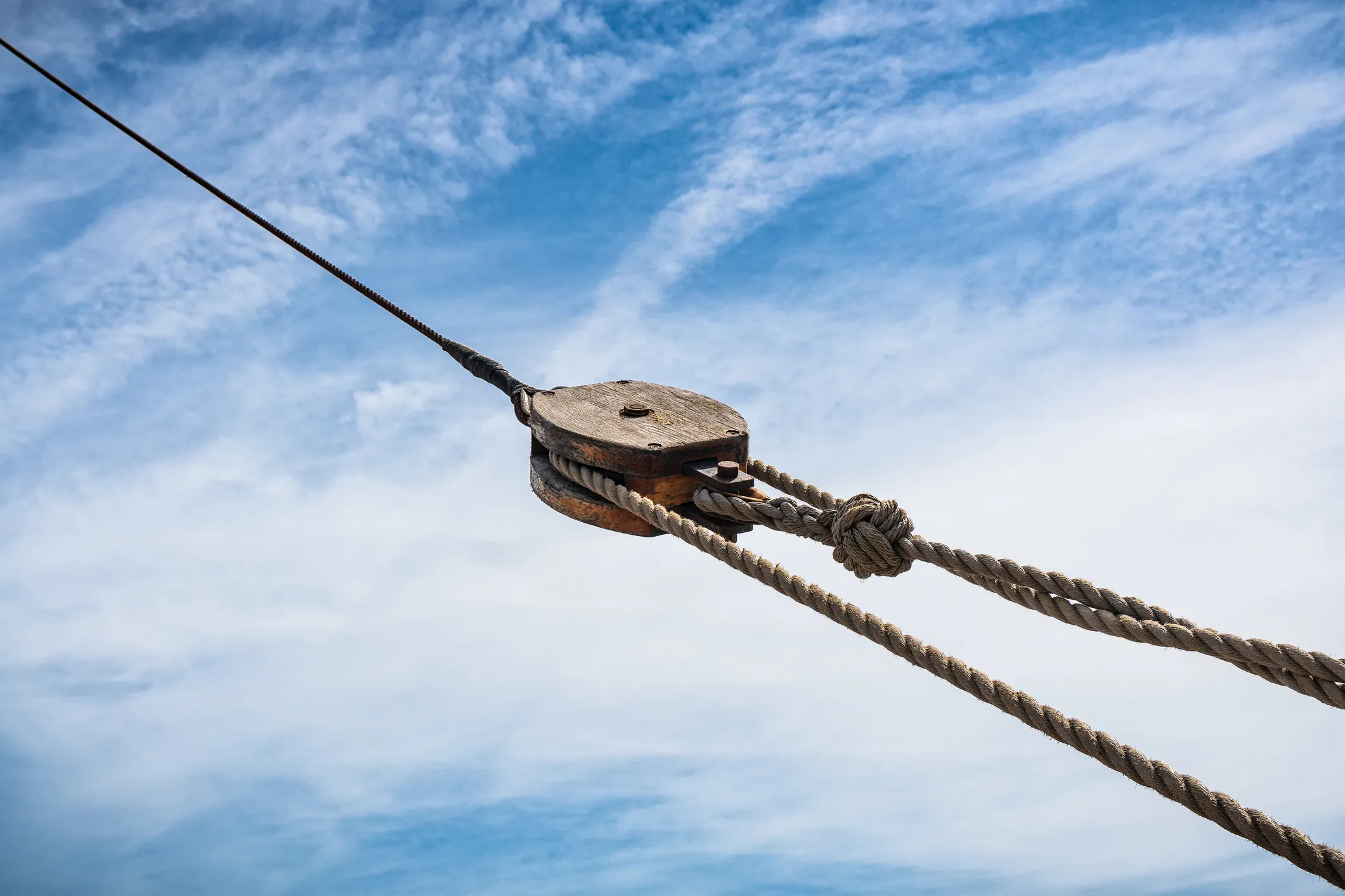 Old wooden pulley on ship before cloudy blue sky