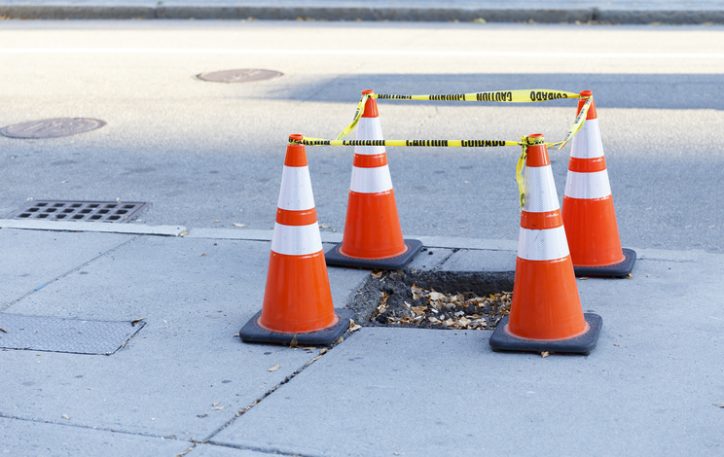 Orange traffic cones supporting ASTM F1637-21 by blocking an unsafe sidewalk.