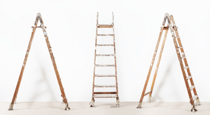 Three wooden ladders that are old and ready to be disposed of properly under ANSI standards.
