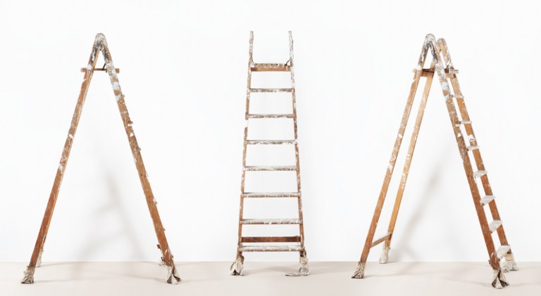 Three wooden ladders that are old and ready to be disposed of properly under ANSI standards.