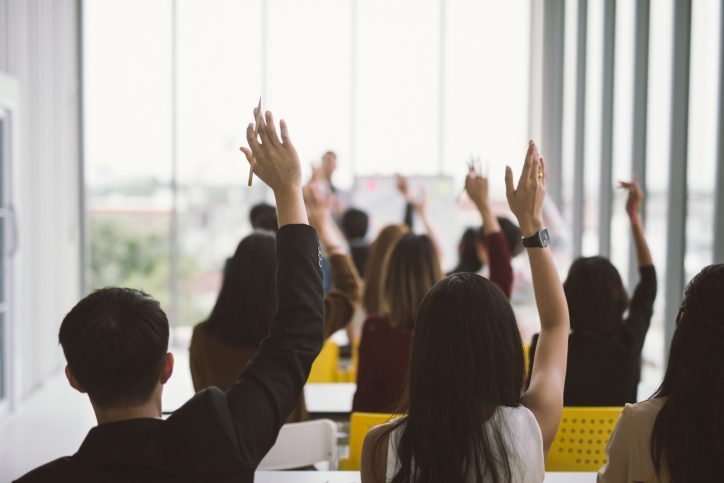 Children raising hands in a classroom with acoustics that meet standards published by ANSI, ASA, and S12