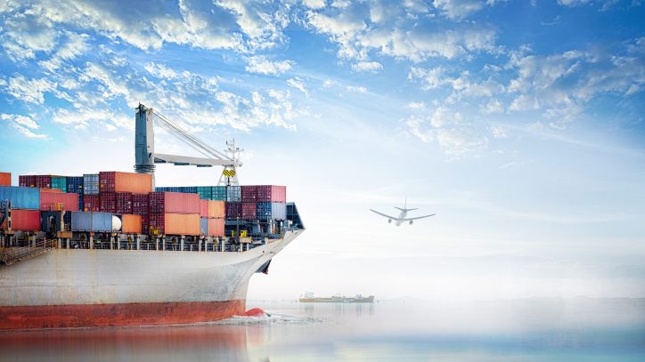 Cargo ship passing under a flying plane. Both are symbols of the global economy and supply-and-demand chains
