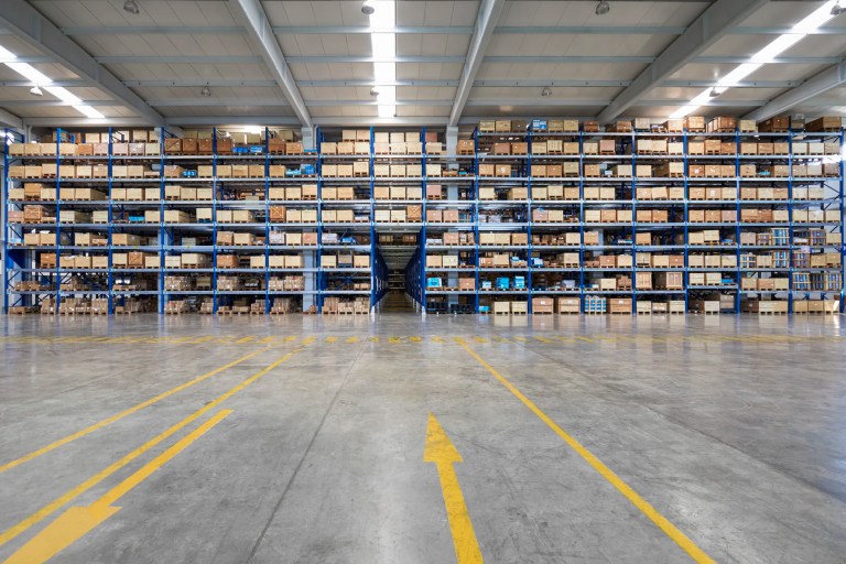 Guided industrial vehicle in warehouse using ANSI/ITSDF B56.5-2024 and automation to stack boxes