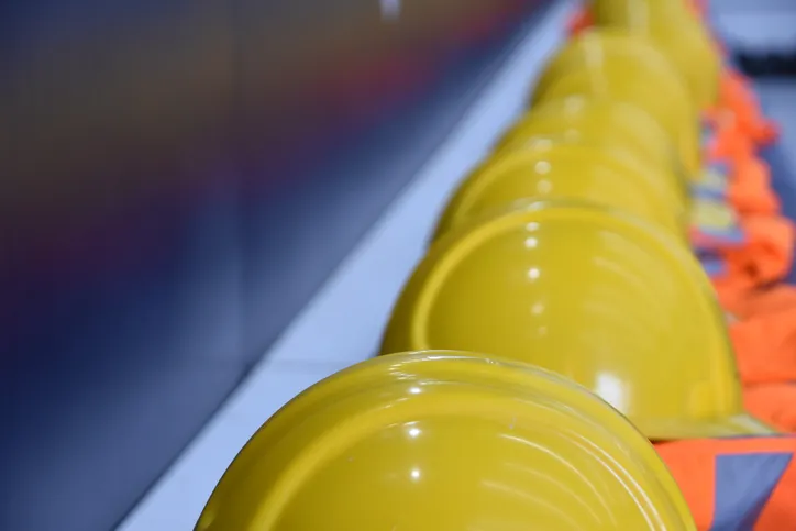 A row of yellow hard helmets that follow ANSI/ASSP Z10.0-2019