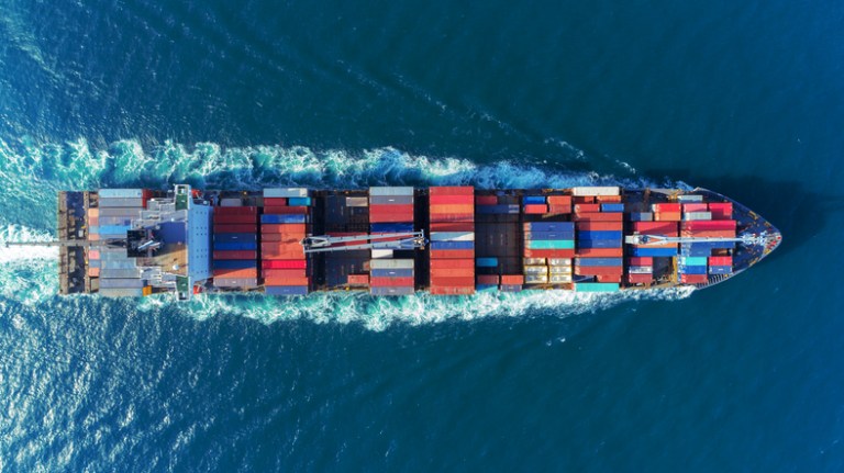Barge crosses the sea with colorful shipping containers, since accreditation delivers confidence in the supply chain.