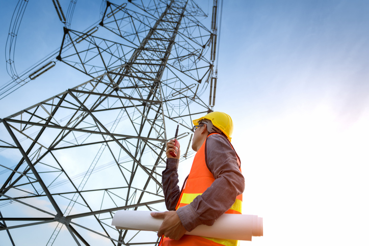 A construction worker looking up at cell site while following ANSI/ASSP Z10.0-2019