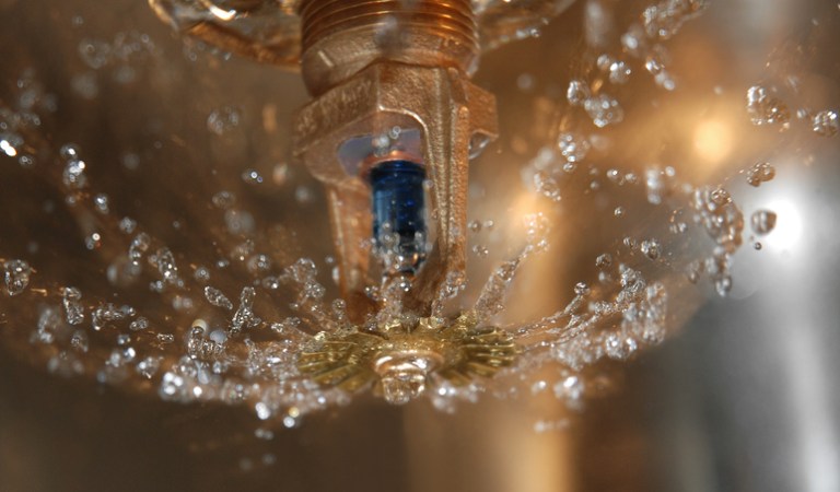 An indoor sprinkler with water coming out of it that is following NFPA 25-2020