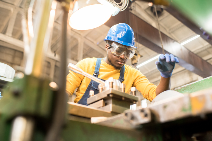 Worker wearing yellow and following a safe hazard zone distance via ISO 13857:2019 to not harm his limb in machinery.